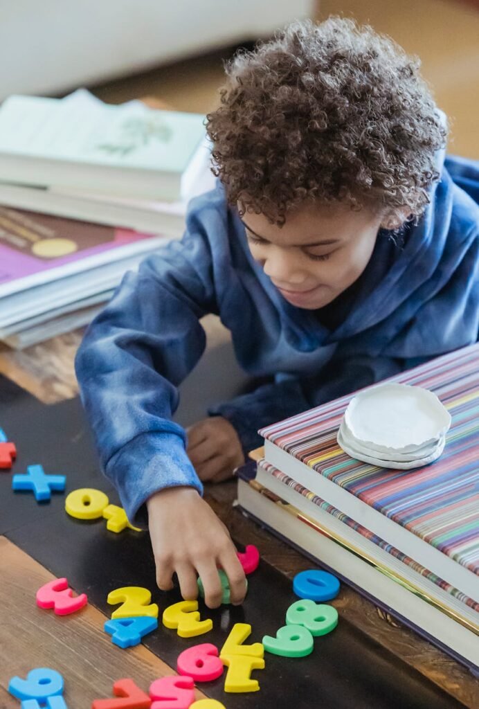 charming ethnic boy playing with toy numbers at table indoors